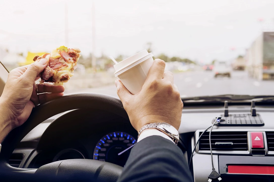 1685316-man-eating-pizza-coffee-while-driving-car-dangerously-min.jpg